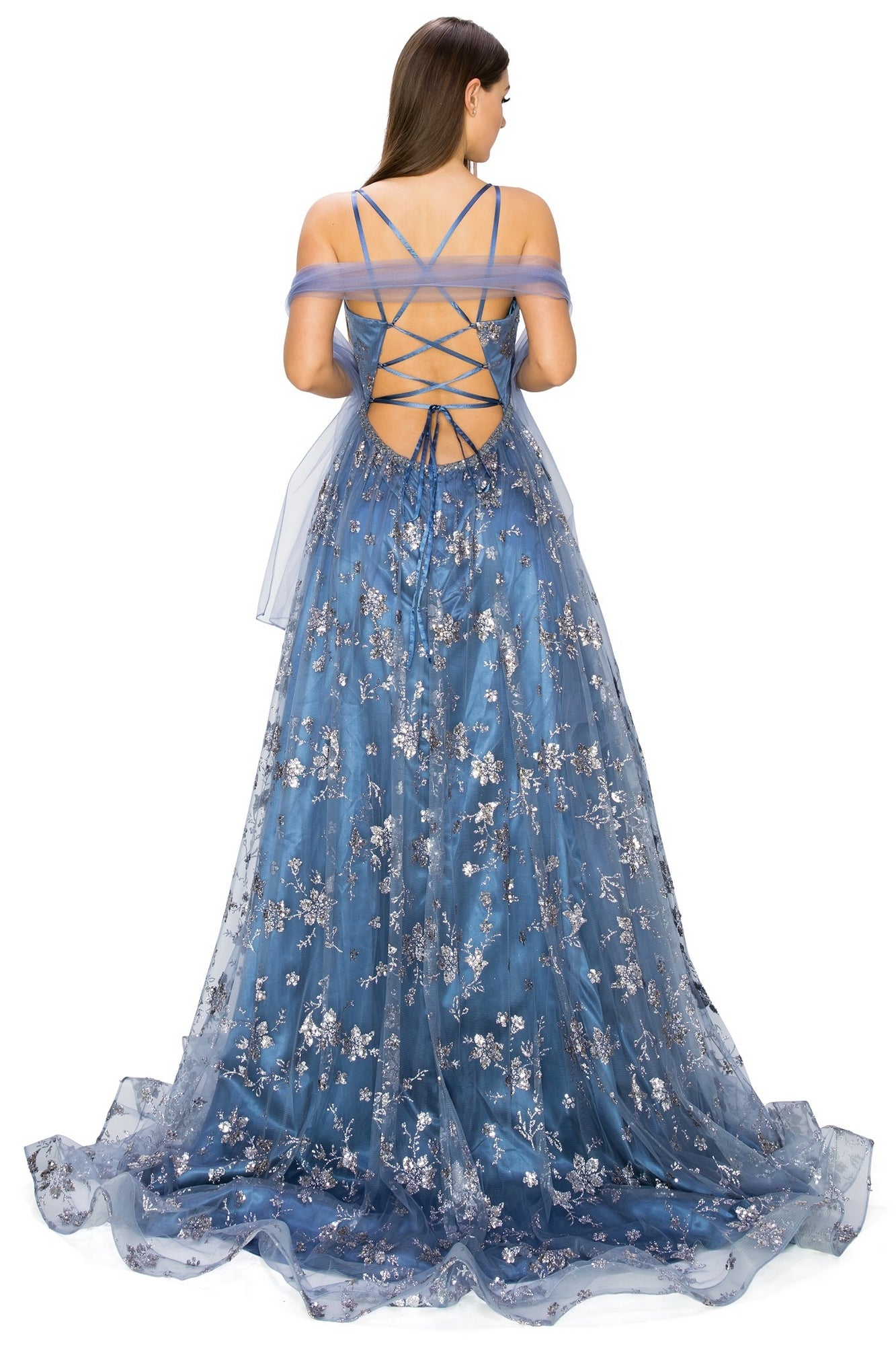 A woman faces away, wearing the Floral-Glitter Long A-Line Formal Prom Dress 8022J—a blue, floor-length gown with silver floral glitter, lace-up back, and off-the-shoulder tulle straps for a stunning prom look.
